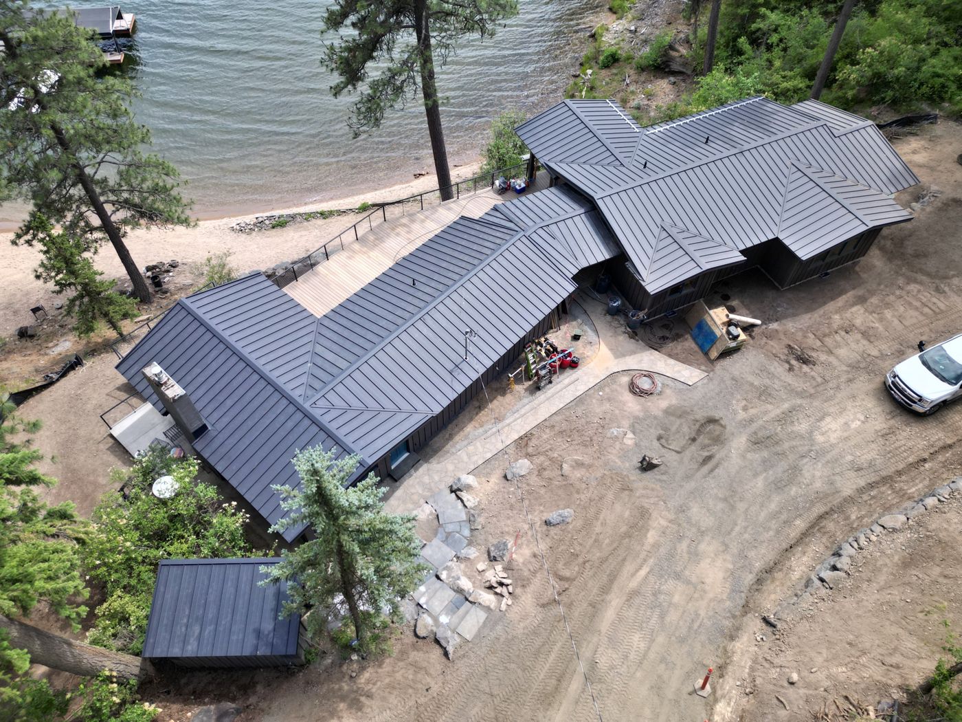 Drone view of a gun metal gray standing seam metal roof on a lakefront home