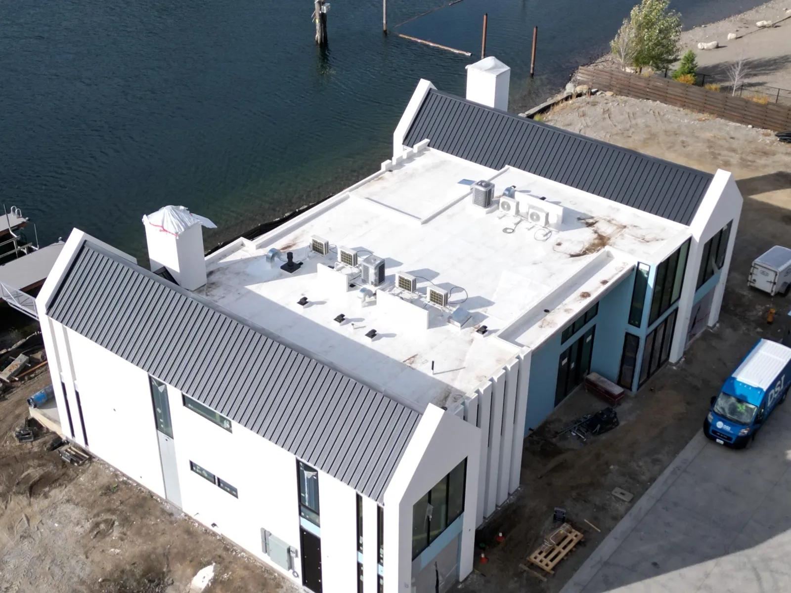 Drone view of a white flat roof on a waterfront building