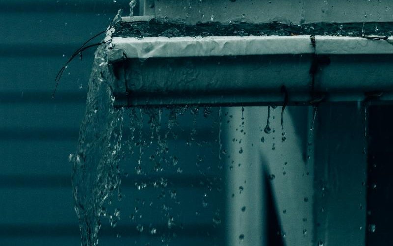 Rainwater spilling over the edge of a gutter during a storm